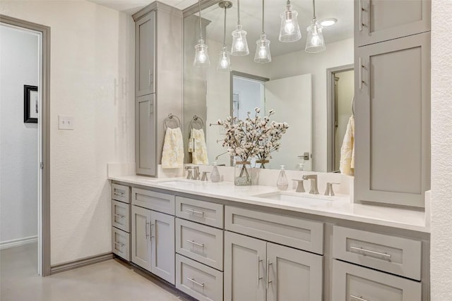 bathroom featuring finished concrete flooring, double vanity, a sink, and baseboards