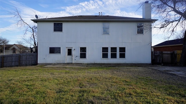 back of property featuring a yard, a chimney, a patio, and fence