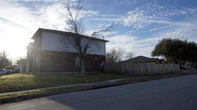 view of side of property featuring stucco siding, fence, and a lawn