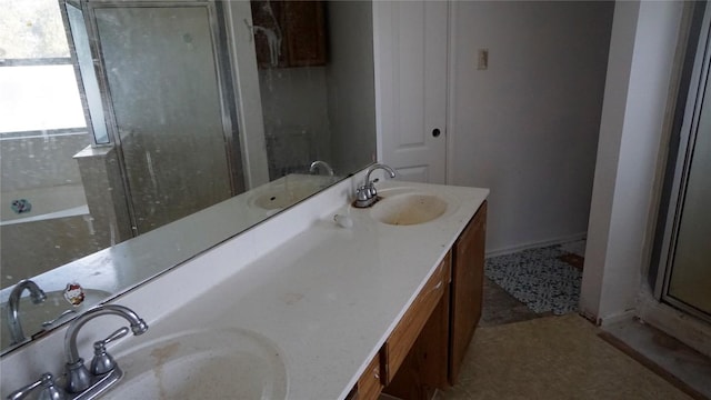 bathroom with double vanity, a stall shower, and a sink