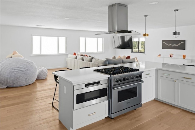 kitchen featuring high end stainless steel range oven, light wood-style flooring, island exhaust hood, and open floor plan