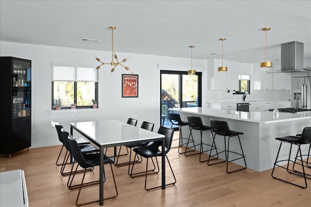 dining area featuring light wood-style floors, visible vents, and a chandelier