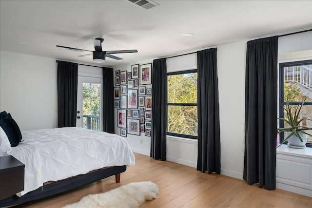 bedroom featuring access to exterior, visible vents, light wood-style floors, a ceiling fan, and baseboards