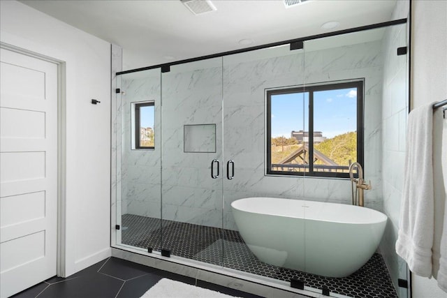 bathroom with a marble finish shower, visible vents, tile patterned flooring, a freestanding tub, and tile walls