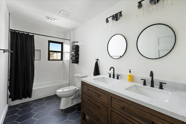 bathroom with toilet, double vanity, a sink, and visible vents