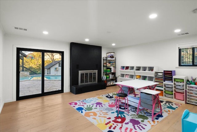 rec room featuring a fireplace, wood finished floors, visible vents, and recessed lighting