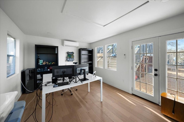 office with french doors, a wall mounted air conditioner, plenty of natural light, and wood finished floors