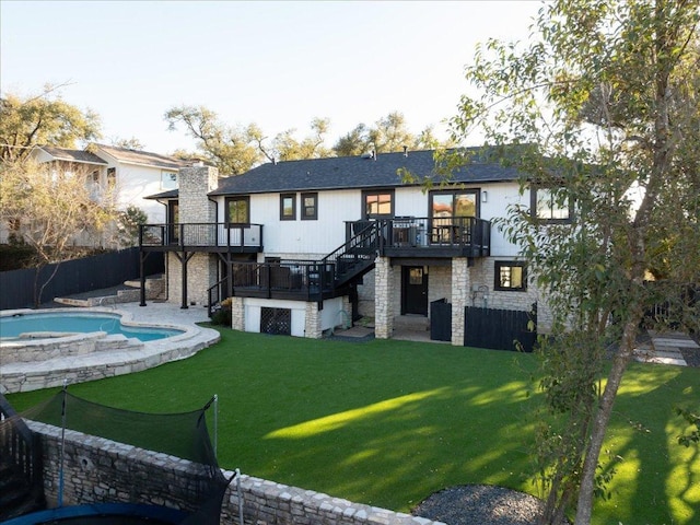 back of property with a deck, stone siding, stairway, and a lawn