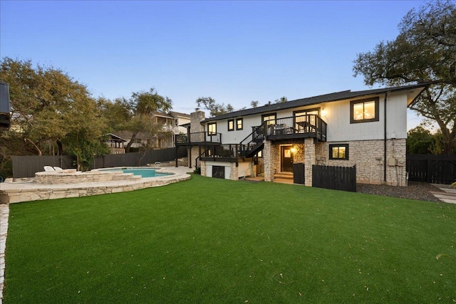 rear view of property with a yard, stairway, a deck, stone siding, and a fenced backyard