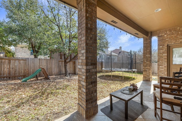 view of patio with a trampoline and a fenced backyard