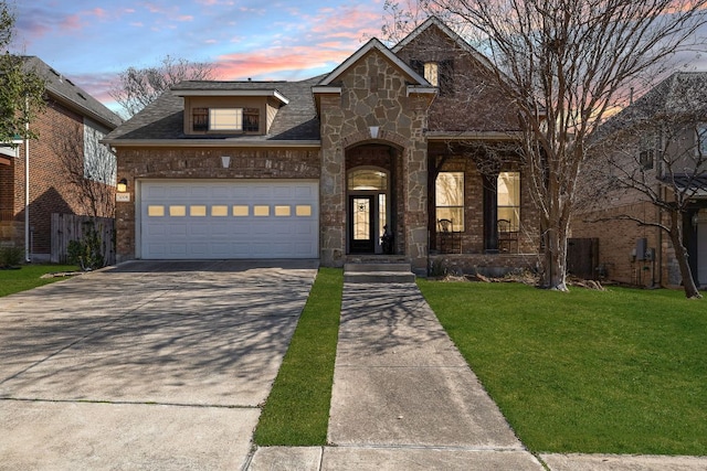 view of front facade featuring a shingled roof, an attached garage, a front yard, stone siding, and driveway