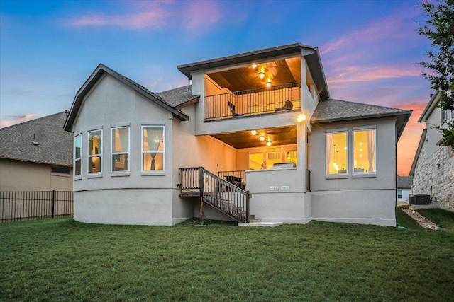 rear view of house featuring stucco siding, a lawn, fence, a balcony, and cooling unit