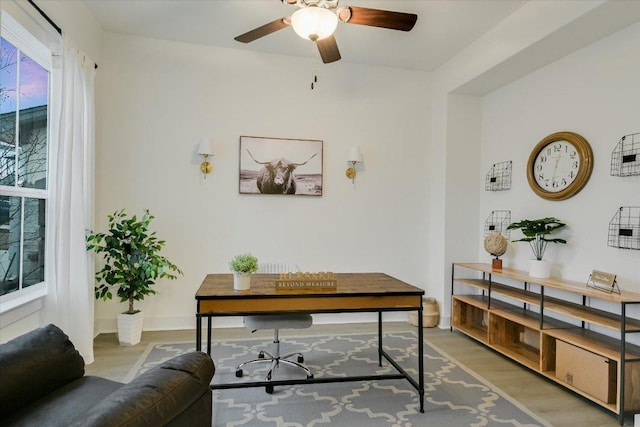 office area with light wood-style flooring, baseboards, and ceiling fan