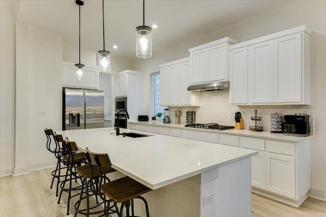 kitchen featuring stainless steel appliances, a sink, a kitchen breakfast bar, range hood, and tasteful backsplash