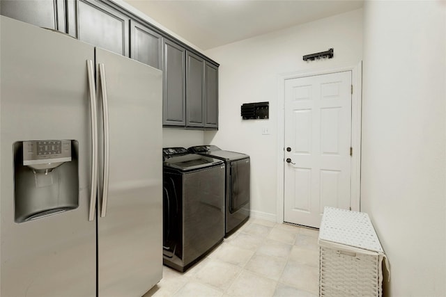 washroom with baseboards, cabinet space, and washing machine and clothes dryer