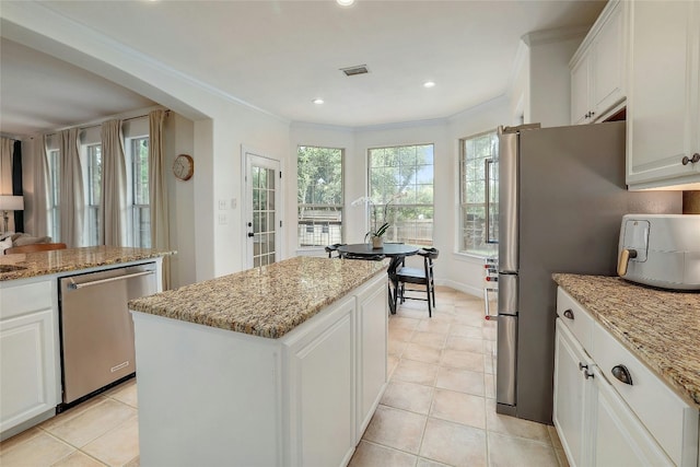 kitchen with appliances with stainless steel finishes, a kitchen island, visible vents, and crown molding