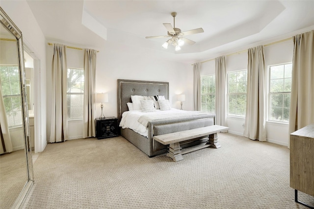 bedroom with a raised ceiling, light carpet, ceiling fan, and baseboards