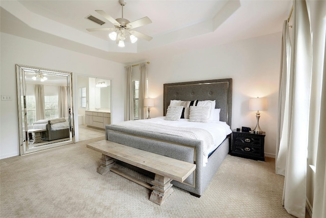 bedroom featuring carpet floors, a raised ceiling, visible vents, ensuite bathroom, and baseboards