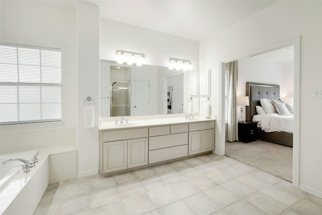 ensuite bathroom with double vanity, a stall shower, a sink, and a bath