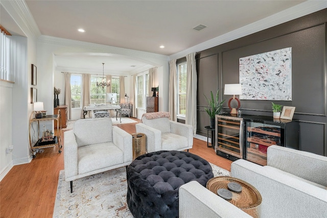 living room featuring visible vents, a chandelier, wood finished floors, and ornamental molding