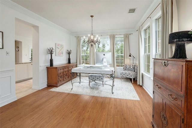 dining area featuring visible vents, crown molding, light wood-type flooring, a chandelier, and a decorative wall