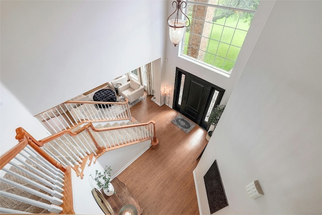 foyer entrance with a towering ceiling, stairway, and wood finished floors