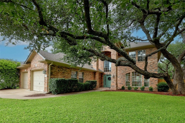 traditional-style home with a garage, driveway, roof with shingles, a front yard, and brick siding