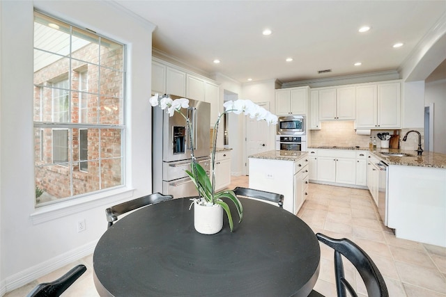 kitchen with appliances with stainless steel finishes, white cabinetry, a sink, and crown molding