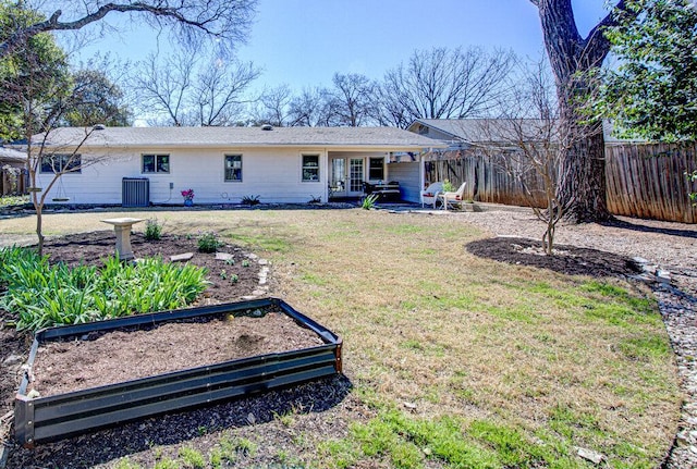 rear view of property with central AC unit, fence, a garden, french doors, and a lawn