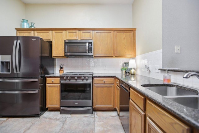 16710 Sabertooth Dr, Round Rock, TX 78681 - kitchen featuring appliances with stainless steel finishes, a sink, tasteful backsplash, brown cabinets, and dark stone counters