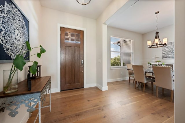 foyer entrance featuring an inviting chandelier, baseboards, and hardwood / wood-style flooring