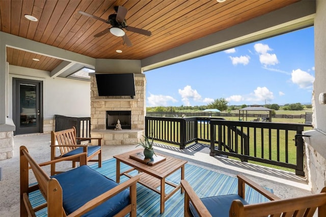 wooden terrace with a yard, a patio area, ceiling fan, and an outdoor living space with a fireplace