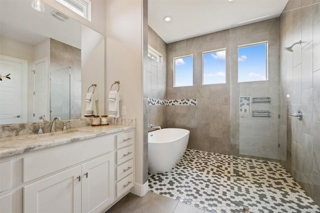 full bath featuring tile patterned flooring, a freestanding bath, vanity, and a walk in shower