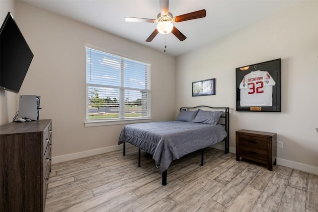 bedroom with light wood-type flooring, baseboards, and a ceiling fan