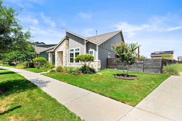 view of side of property with stone siding, board and batten siding, fence, and a lawn