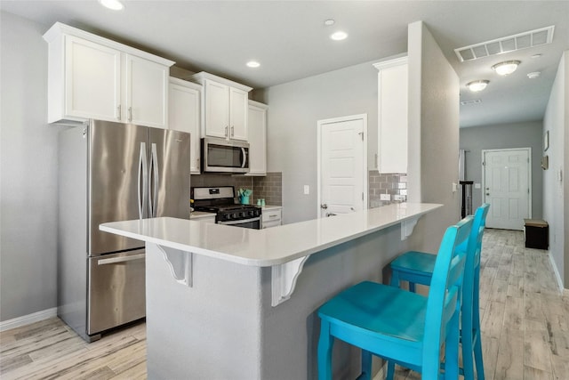 kitchen with appliances with stainless steel finishes, light countertops, white cabinets, and visible vents