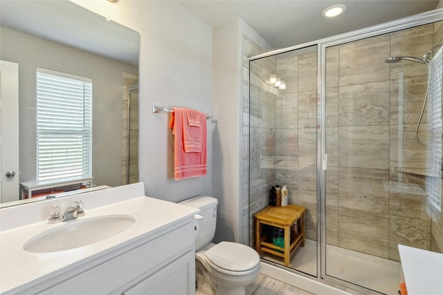 full bathroom featuring vanity, a shower stall, and toilet