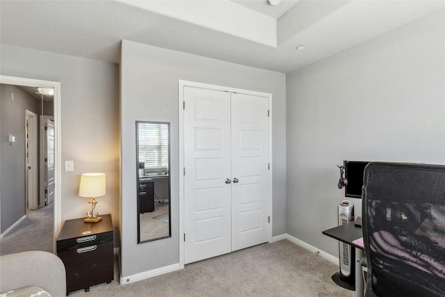 bedroom with baseboards, a closet, and light colored carpet