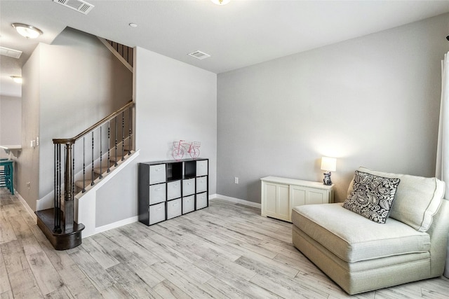 sitting room featuring stairway, light wood-style flooring, visible vents, and baseboards