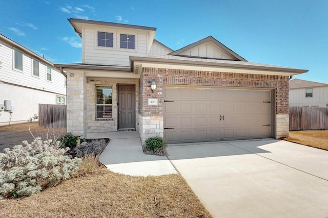 view of front of home with concrete driveway, stone siding, an attached garage, fence, and board and batten siding