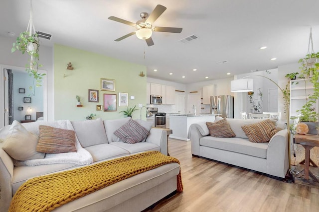 living room with visible vents, ceiling fan, light wood-style flooring, and recessed lighting