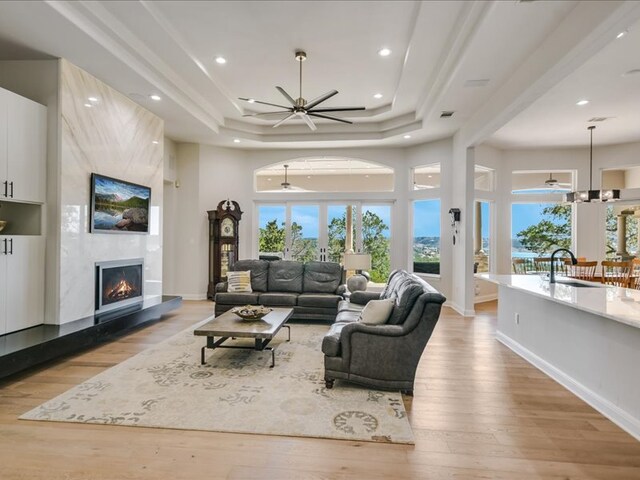 living area with plenty of natural light, light wood-type flooring, a large fireplace, and a ceiling fan