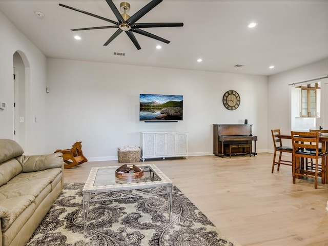 living room featuring baseboards, visible vents, arched walkways, light wood-type flooring, and recessed lighting