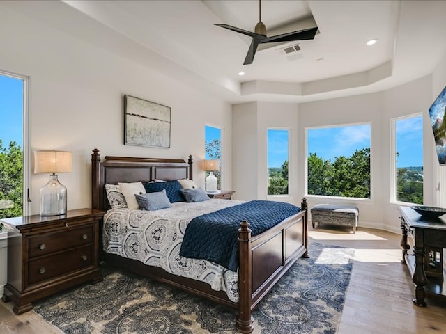 bedroom with recessed lighting, a raised ceiling, visible vents, wood finished floors, and baseboards