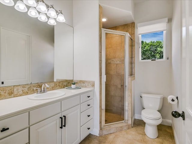 bathroom featuring toilet, a stall shower, vanity, baseboards, and tile patterned floors