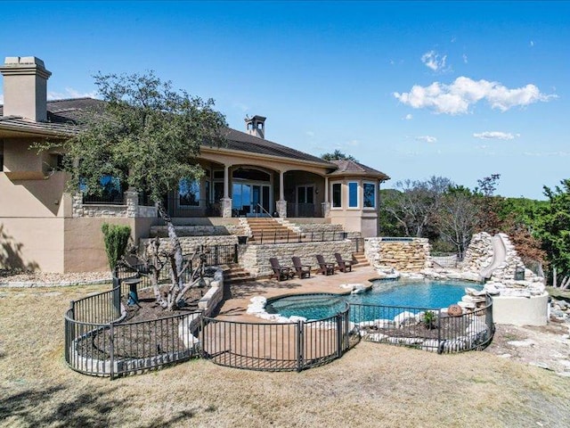 view of swimming pool featuring a water slide, a jacuzzi, stairs, a fenced in pool, and a patio area