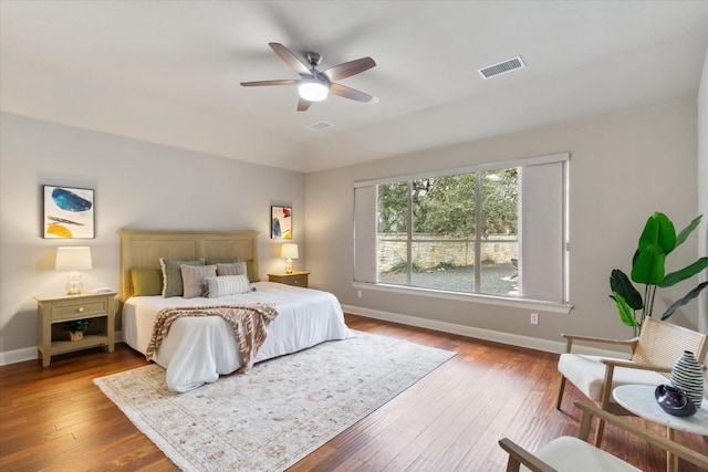 bedroom with ceiling fan, wood-type flooring, visible vents, and baseboards