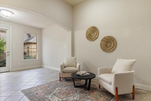 living area with arched walkways, visible vents, baseboards, and light tile patterned floors