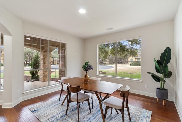 dining room featuring arched walkways, visible vents, baseboards, and wood finished floors