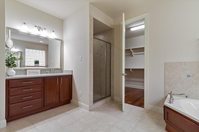 bathroom featuring a stall shower, tile patterned floors, a garden tub, a walk in closet, and vanity